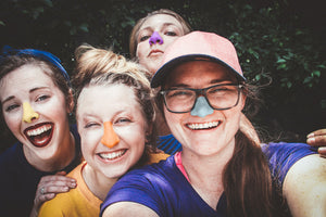 Group of women wearing Nöz colorful sunscreen on their noses. 